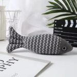 Grey striped fish cat toy with zigzag pattern on a desk.
