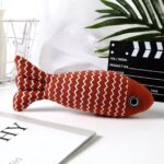 Red striped fish cat toy with zigzag pattern on a desk.