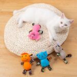 White cat lying amongst plush floral animal toys on cushion