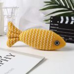 Yellow striped fish cat toy with zigzag pattern on a desk.